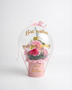 Pink floral arrangement in a transparent dome with 'Best wishes on your new journey' text, full product view