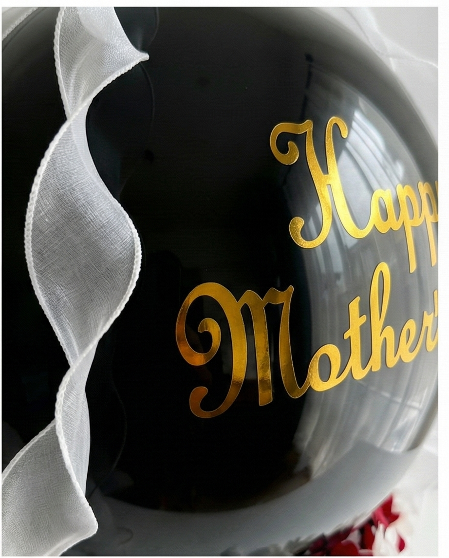 Black balloon with 'Happy Mother's Day' text and flowers, placed in a decorative box, slight right close up
