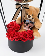 Decorative balloon with gold balloons, teddy bear, and red roses inside a clear dome, teddy bear and flowers close up