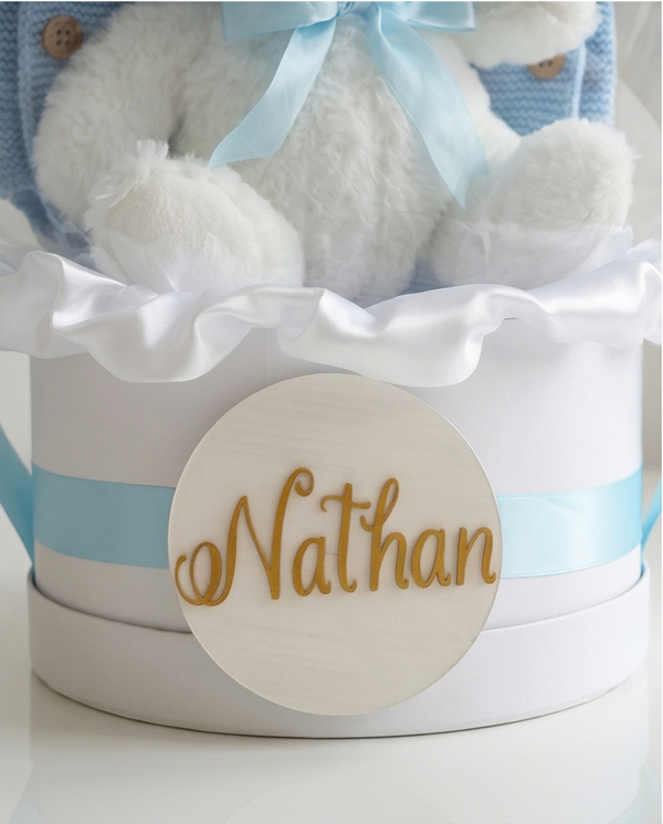 Baby gift set with teddy bear, blue romper, and 'Welcome Baby' text in a clear dome, name close up