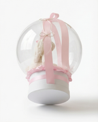 Teddy bear in a clear dome with pink ribbons, back view