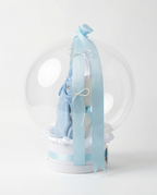 Baby gift set with teddy bear, blue romper, and 'Welcome Baby' text in a clear dome, side view
