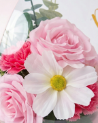 Pink floral arrangement in a transparent dome with 'Best wishes on your new journey' text, flower close up