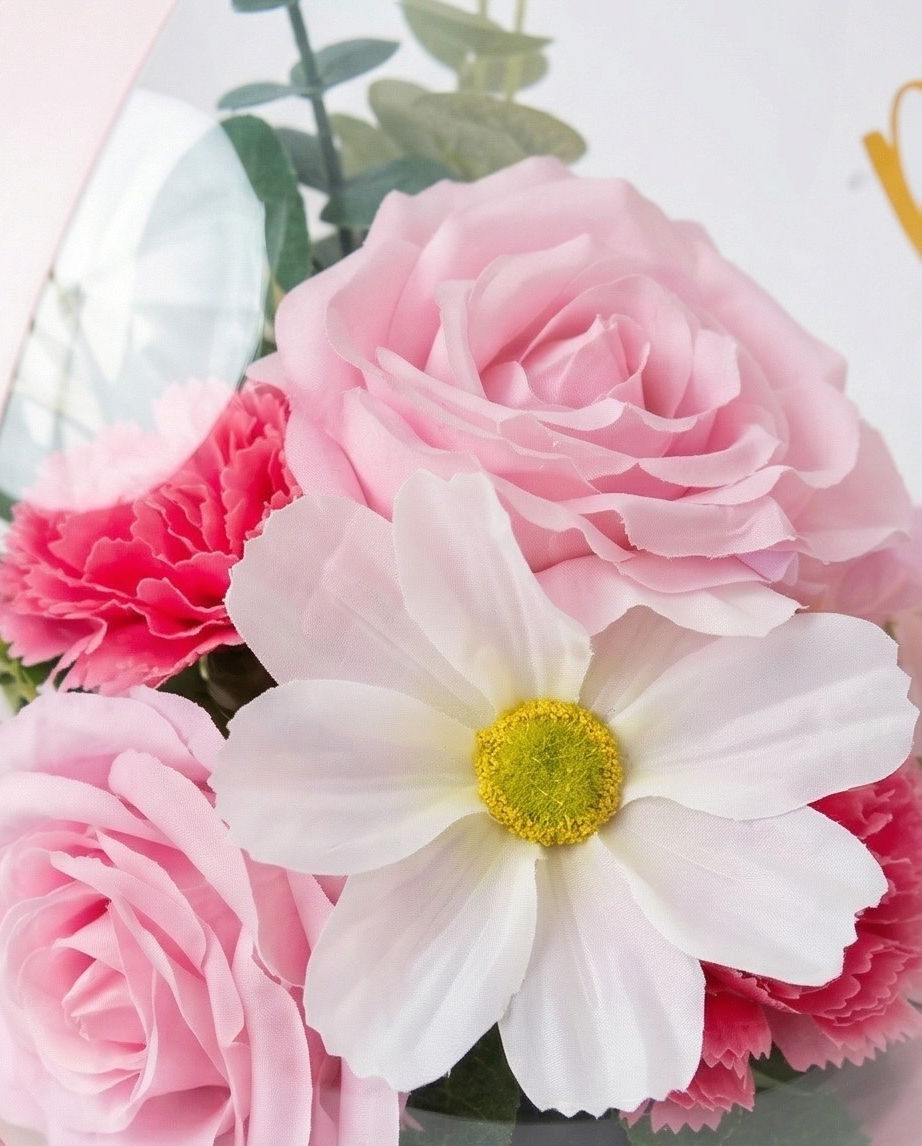 Pink floral arrangement in a transparent dome with 'Best wishes on your new journey' text, flower close up
