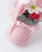 Pink floral arrangement in a transparent dome with 'Best wishes on your new journey' text, pink holder close up