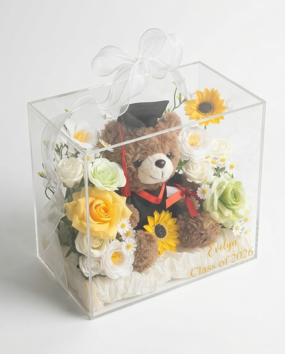 Graduation-themed teddy bear with flowers in a clear gift bag, full product view slight top right